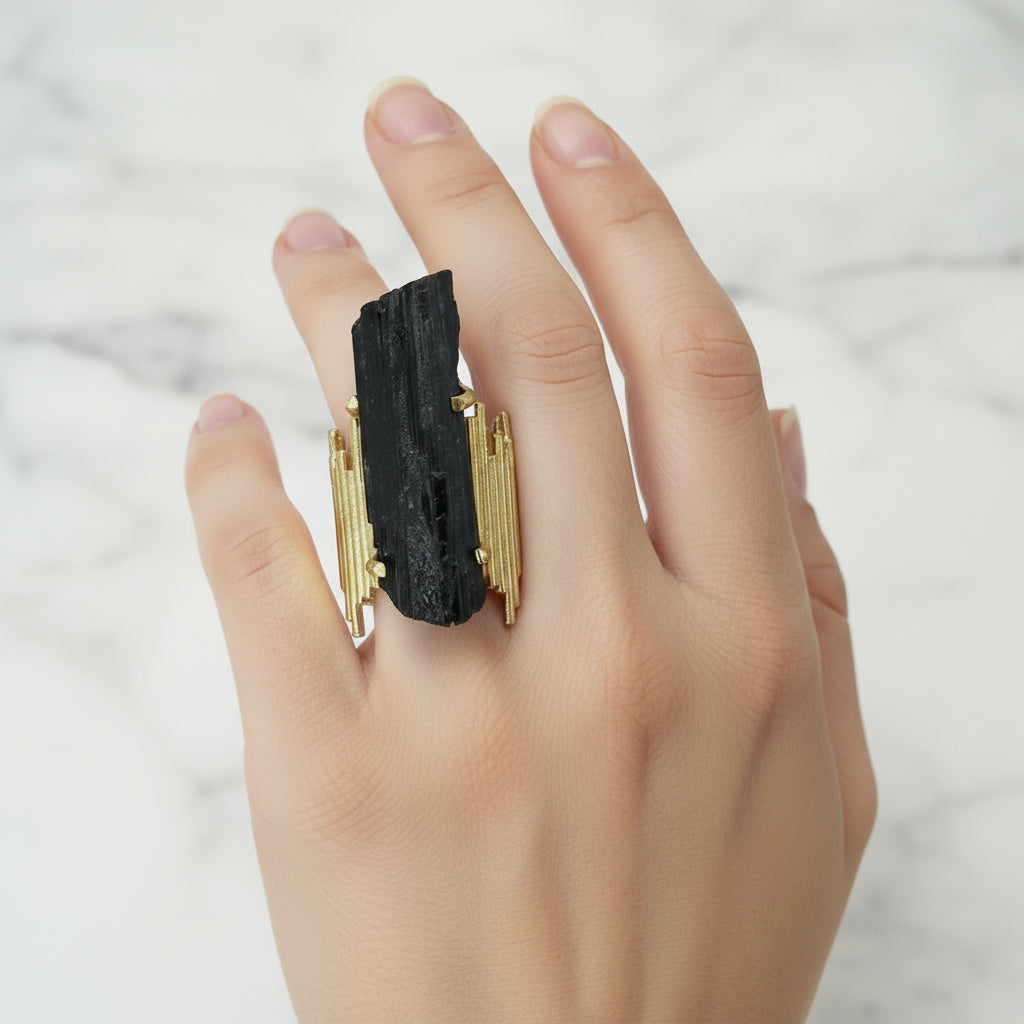 Hand wearing a black and gold ring on a white background