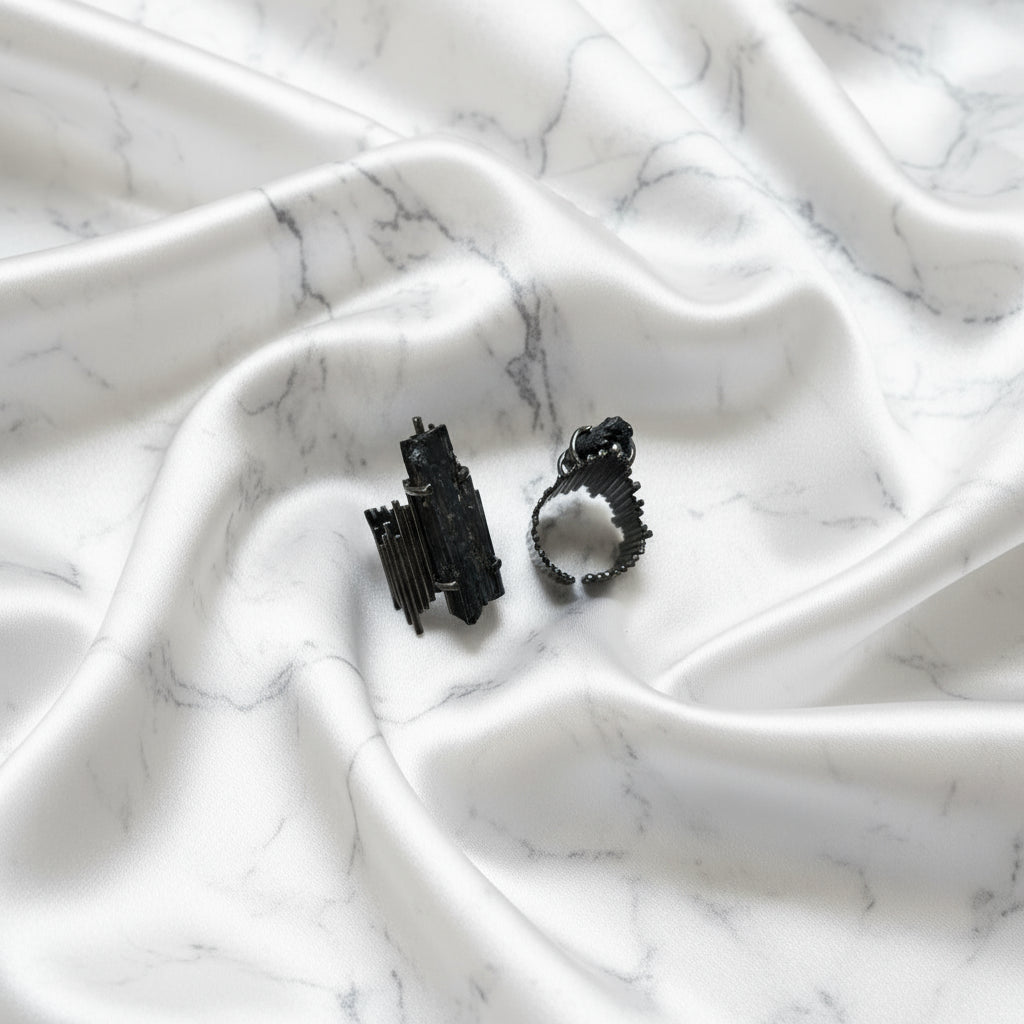 Black stone-like jewelry piece with a ring on a white background